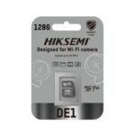 HIKSEMI DE1 128GB Class 10 V30 MicroSDXC memory card placed next to a smart home Wi-Fi security camera, highlighting continuous video storage.